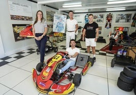 Ángela, Andrés y Efrén posan de pie con Ander subido a un monoplaza.