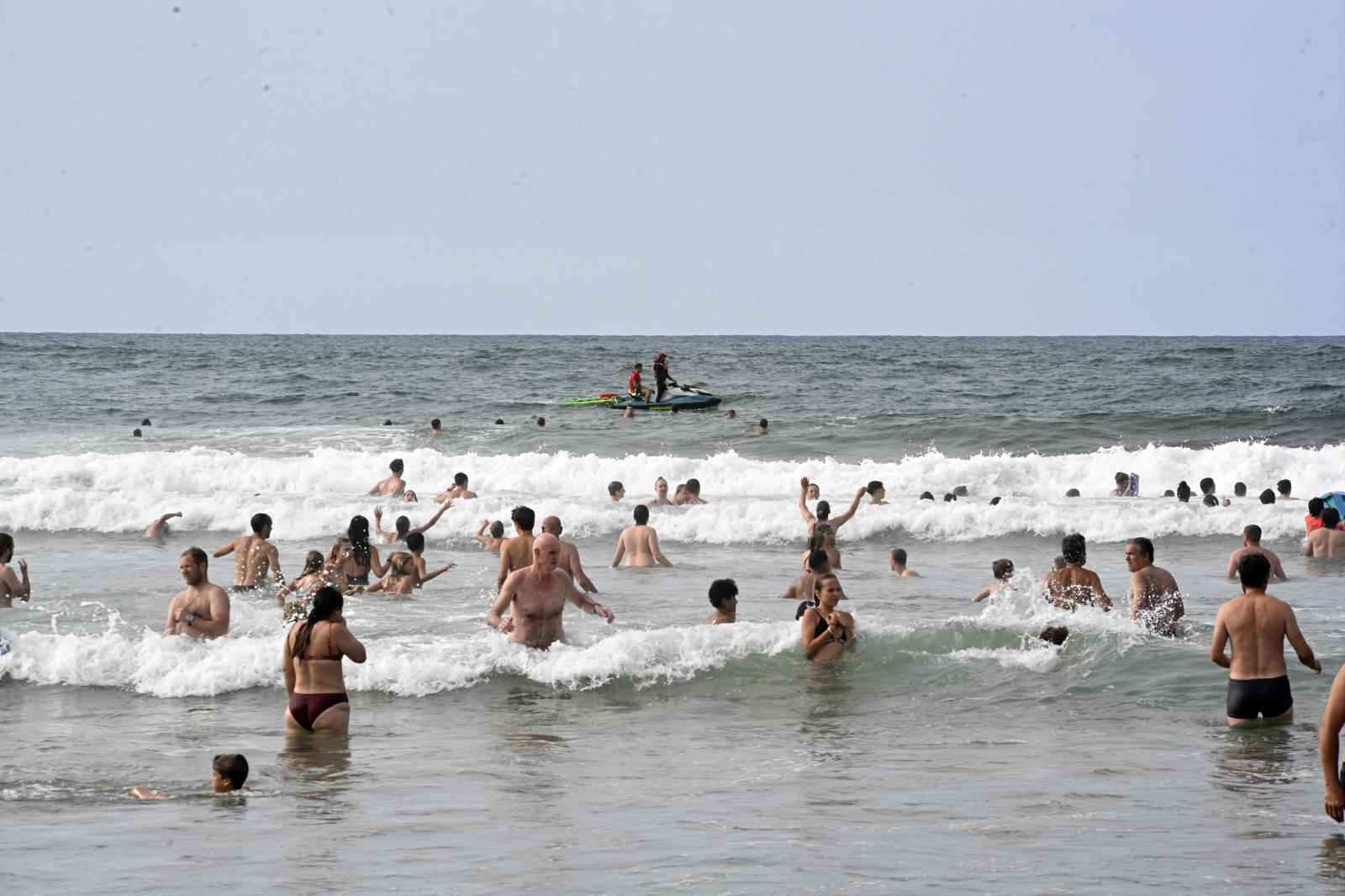 Gente bañándose en la playa de Zurriola.