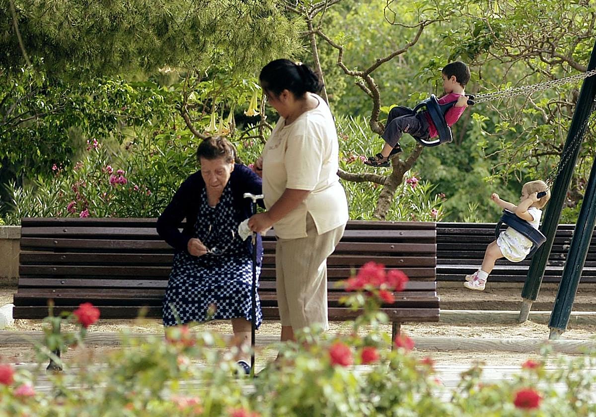Una mujer nacida en el extranjero cuida de una anciana en un parque.