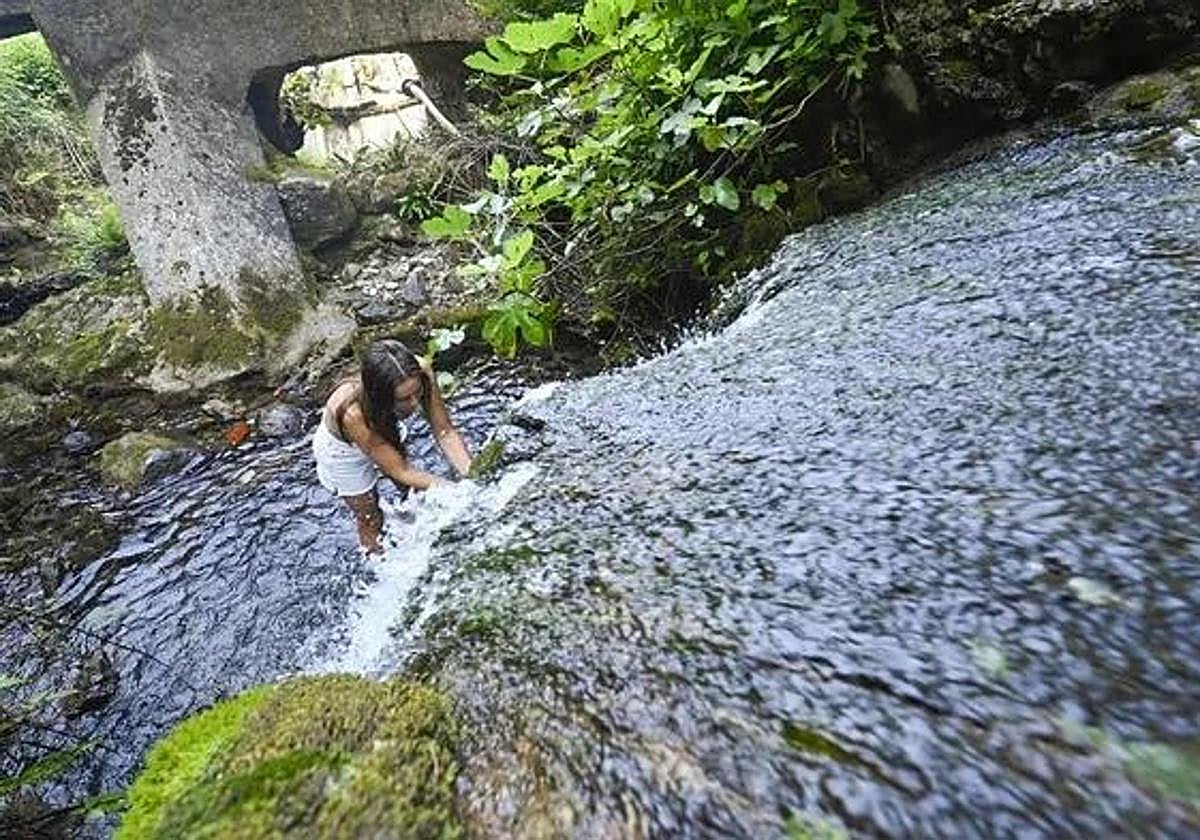 Una joven se refresca en un pequeño arroyo en las cercanías de Tolosa.