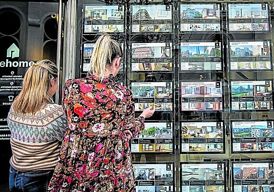 Dos mujeres observan el escaparate de una inmobiliaria. Estas han canalizado en vivienda usada ocho de cada diez ventas.