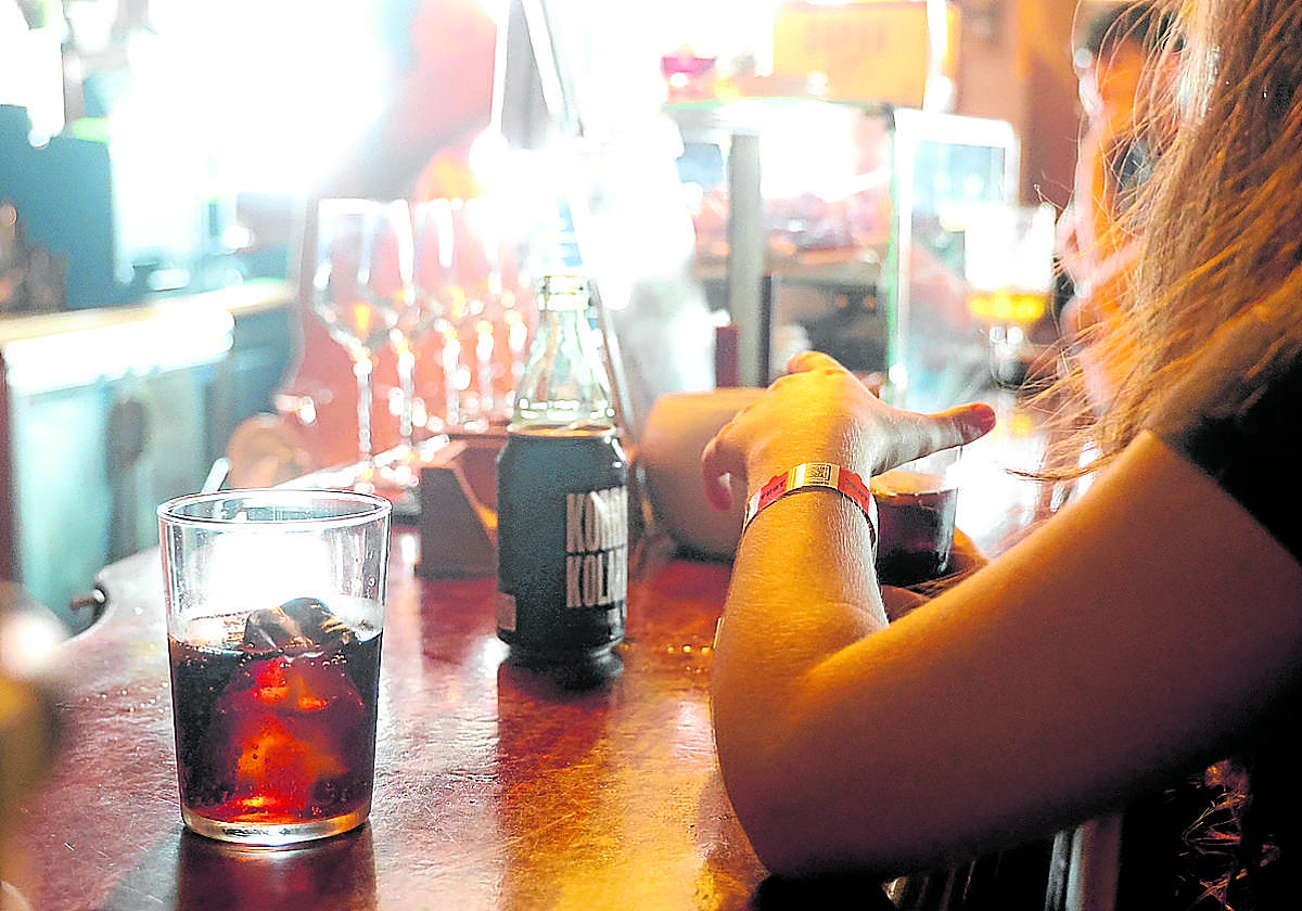 Una mujer tomando una bebida en un establecimiento de Zarautz, con la pulsera en la muñeca.