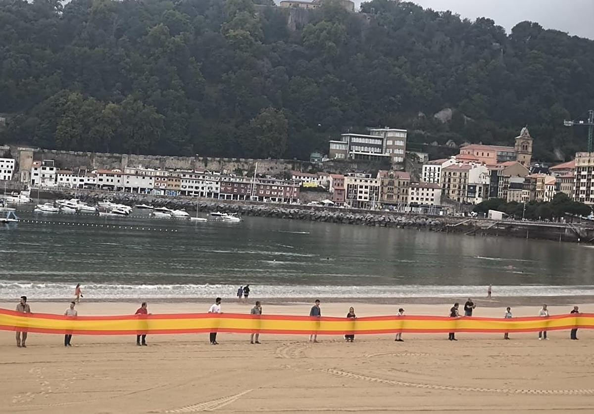 Los miembros de Vox agarran la bandera en el arenal donostiarra este martes.