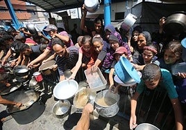 Palestinos aguardan para recoger algo de comida en Ciudad de Gaza.