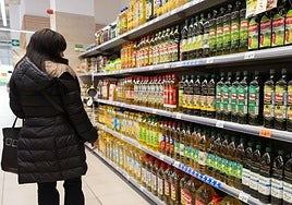 Una mujer observa el surtido de aceite de oliva en un supermercado.