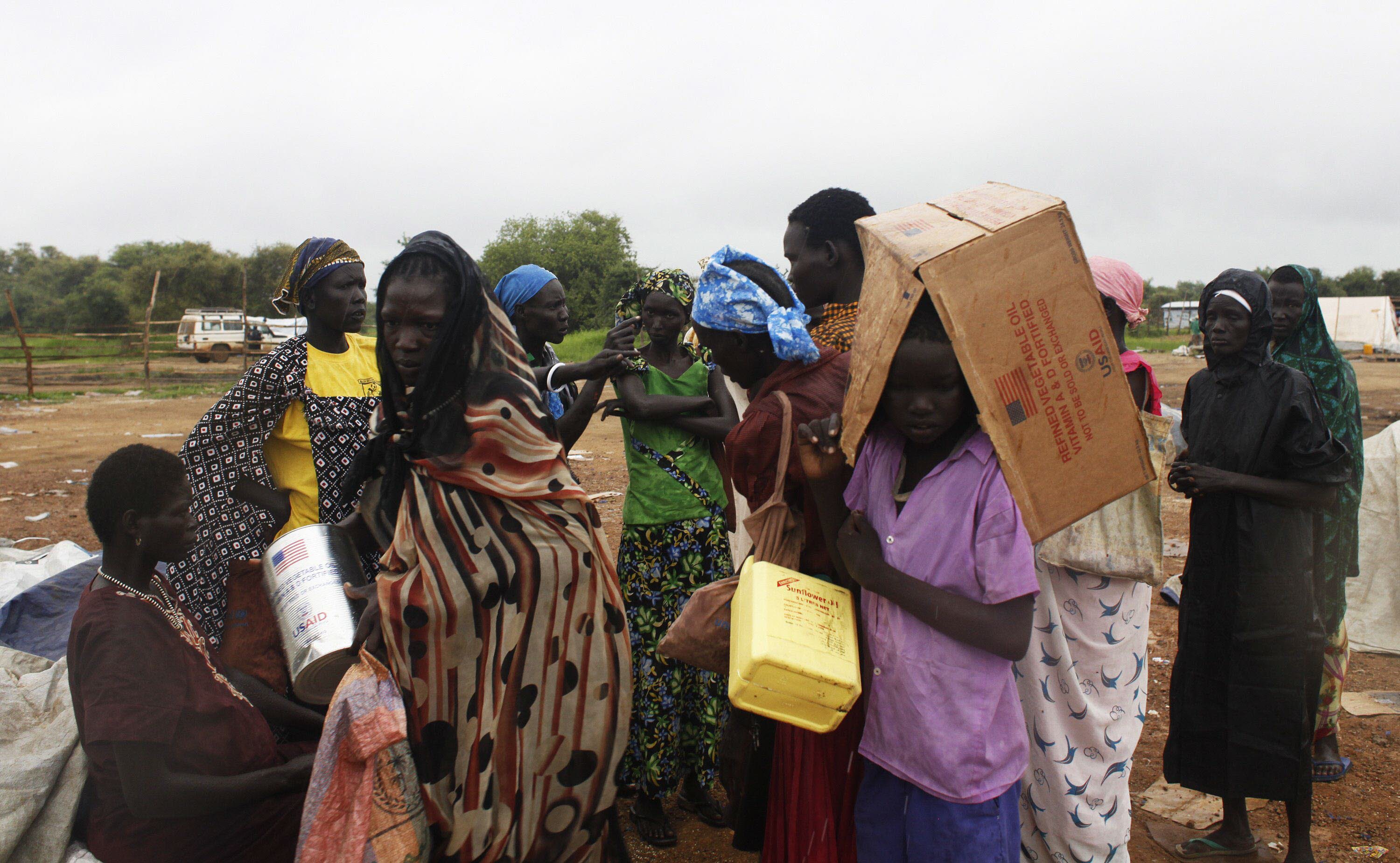 Varias personas se protegen de la lluvia después de recoger comida en Minkaman