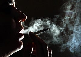 Una joven exhala el humo tras dar una calada a un porro de cannabis, cuyo consumo ha descendido entre adolescentes.