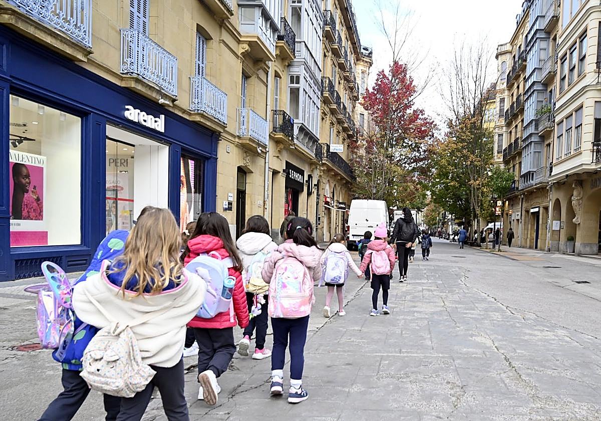 Varios niños se dirigen al colegio por el centro de Donostia.