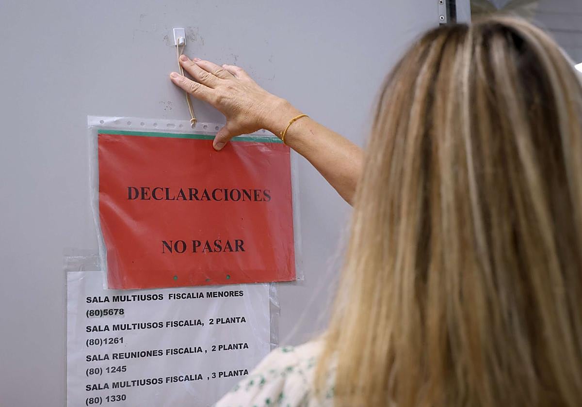 Una funcionaria de Justicia coloca un cartel de advertencia en una de las salas del interior de la Fiscalía de Menores, ubicada en San Sebastián.