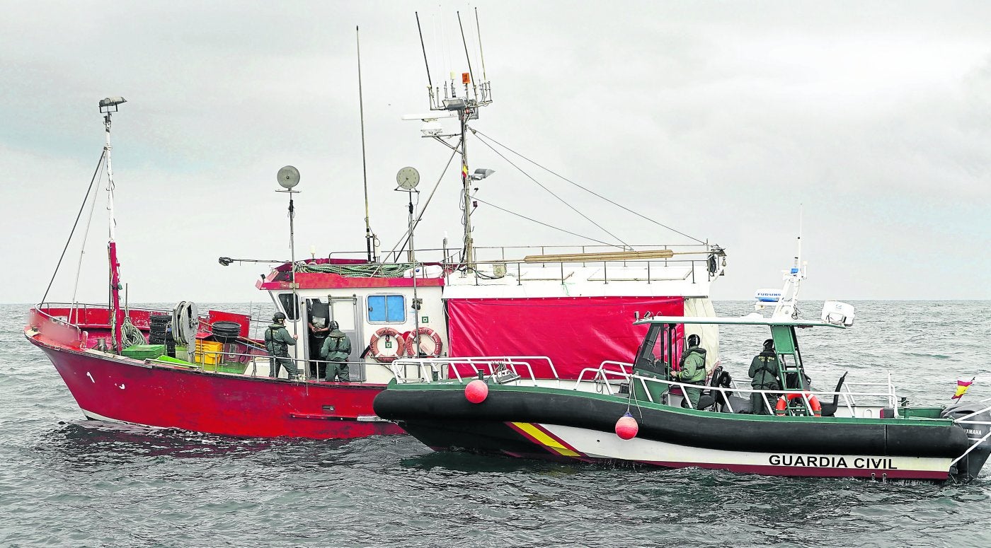 Dos agentes realizan la inspección a un pesquero mientras son supervisados por el resto desde la patrullera.