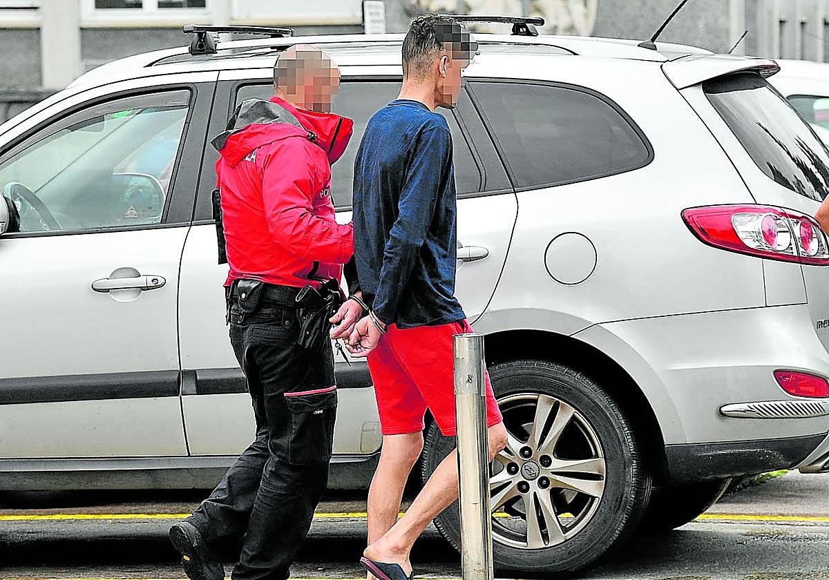 Dos agentes de la Ertzaintza conducen a un detenido a dependencias judiciales en Donostia.