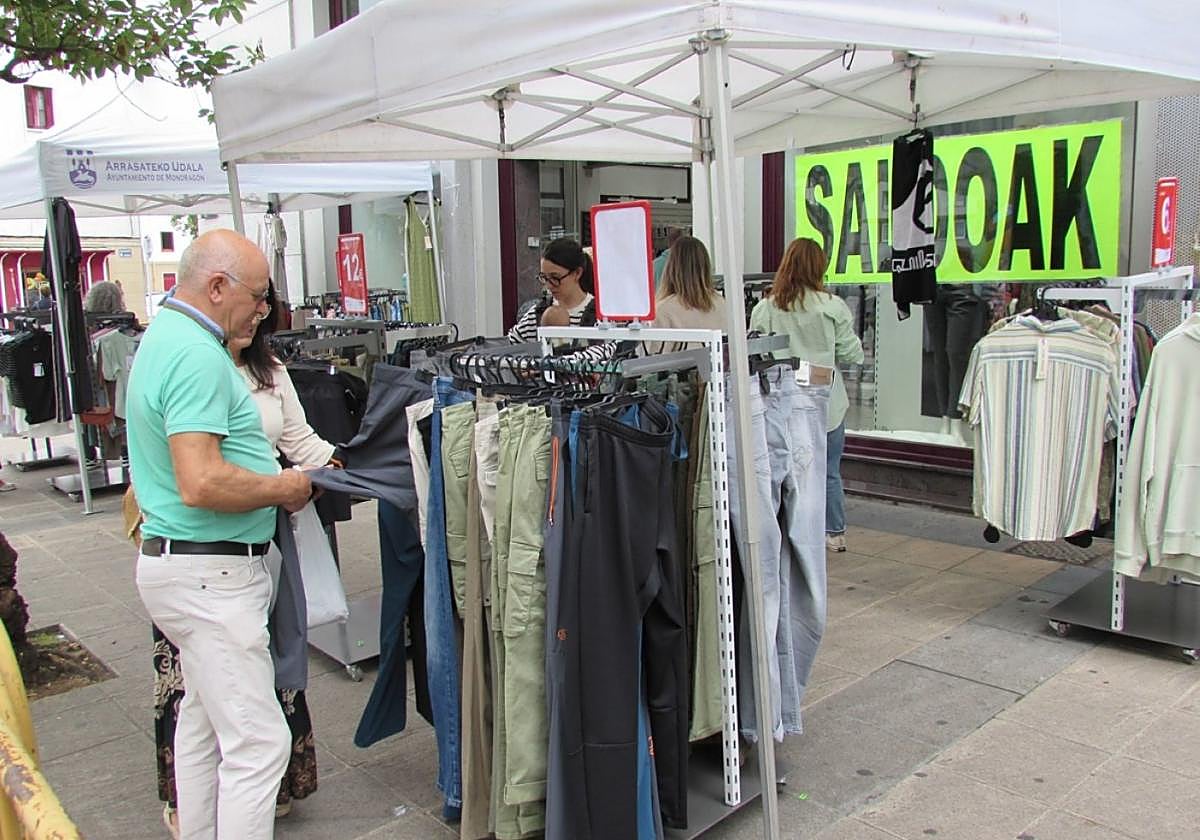 Varias personas observan las prendas expuestas bajo la carpa frente a Loramendi Kirolak.