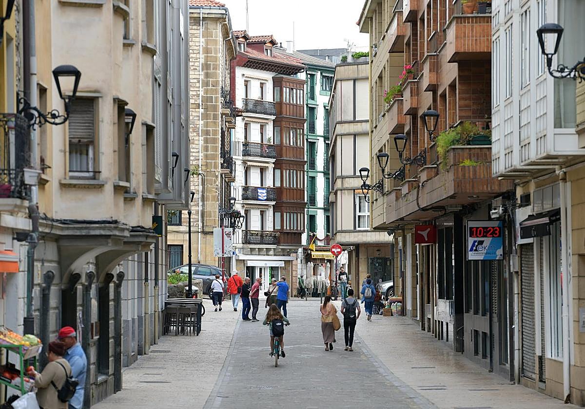 Varias personas caminan o hacen compras en una calle de Zumaia.