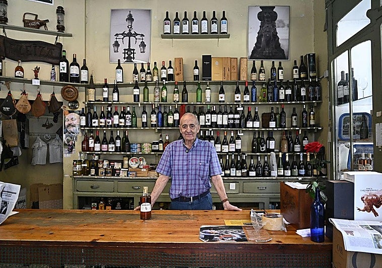 Bernardo Anabitarte posa detrás del mostrador y delante de las estanterías en Vinos Ezeiza.