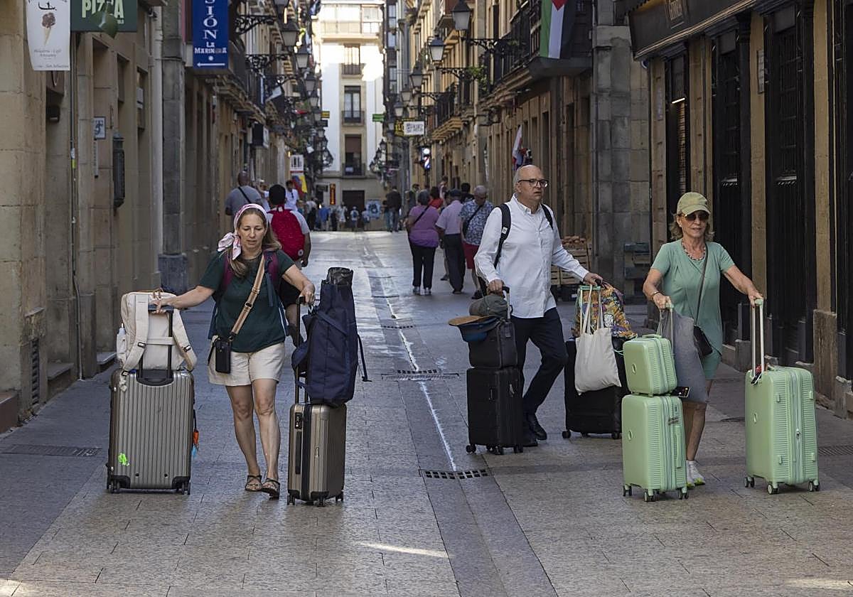 Turistas con maletas por la Parte Vieja donostiarra.