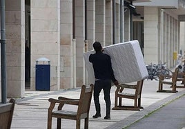Un hombre lleva un colchón a un domicilio.