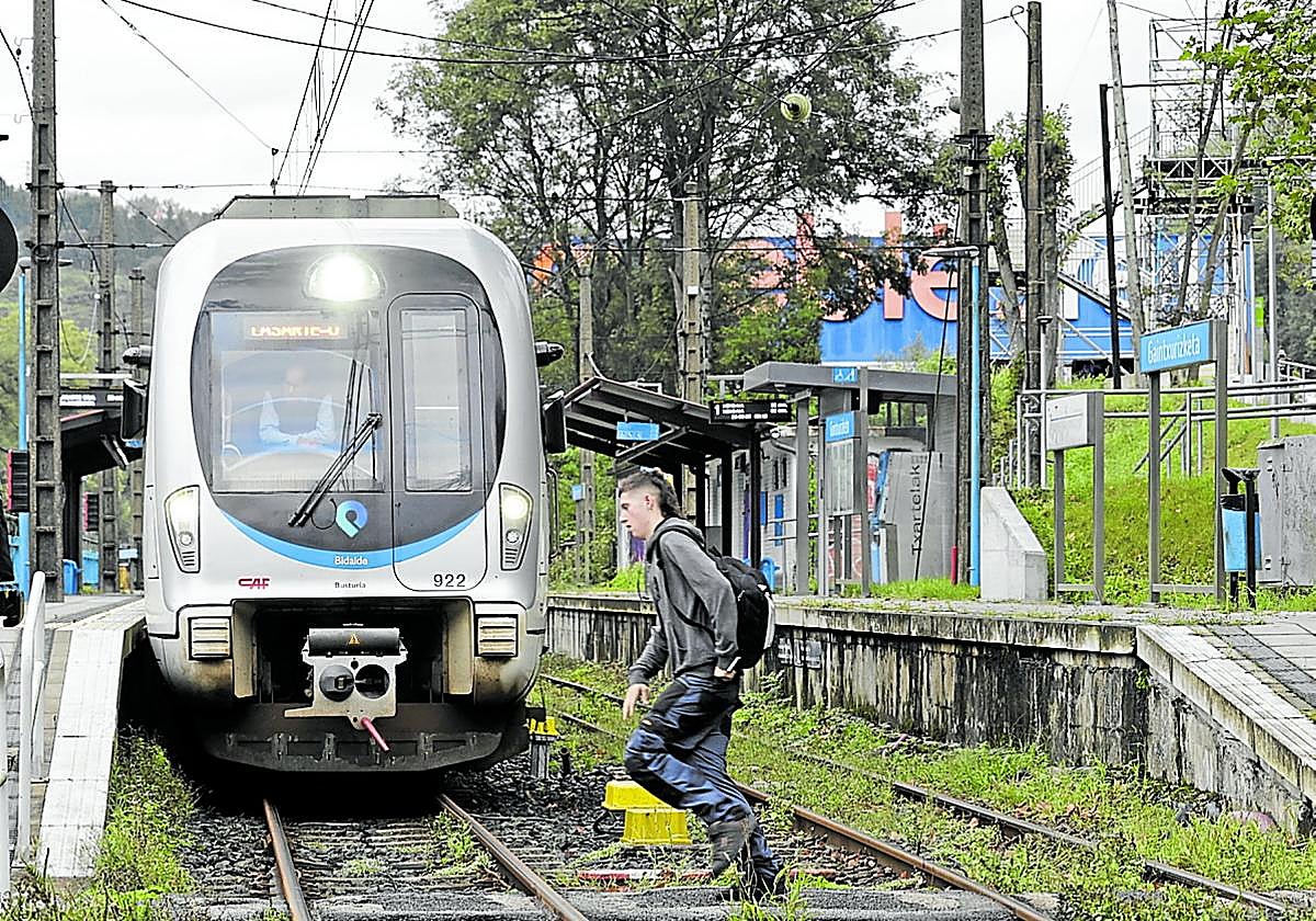Un joven cruza el paso a nivel de Gaintxurizketa. Arriba a la derecha se ve la pasarela provisional.