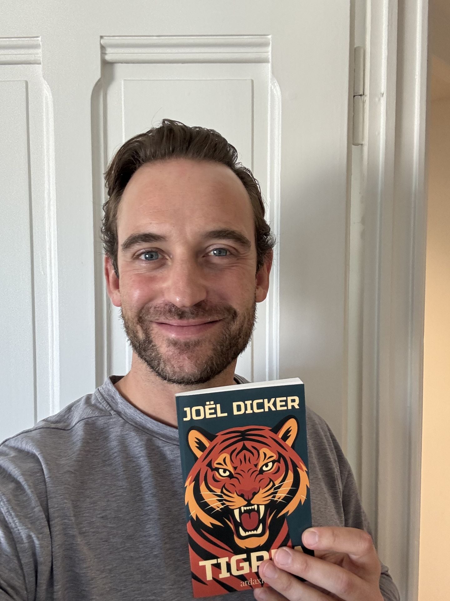 Joël Dicker idazlea, euskarara ekarri duten edizioarekin eskuetan.