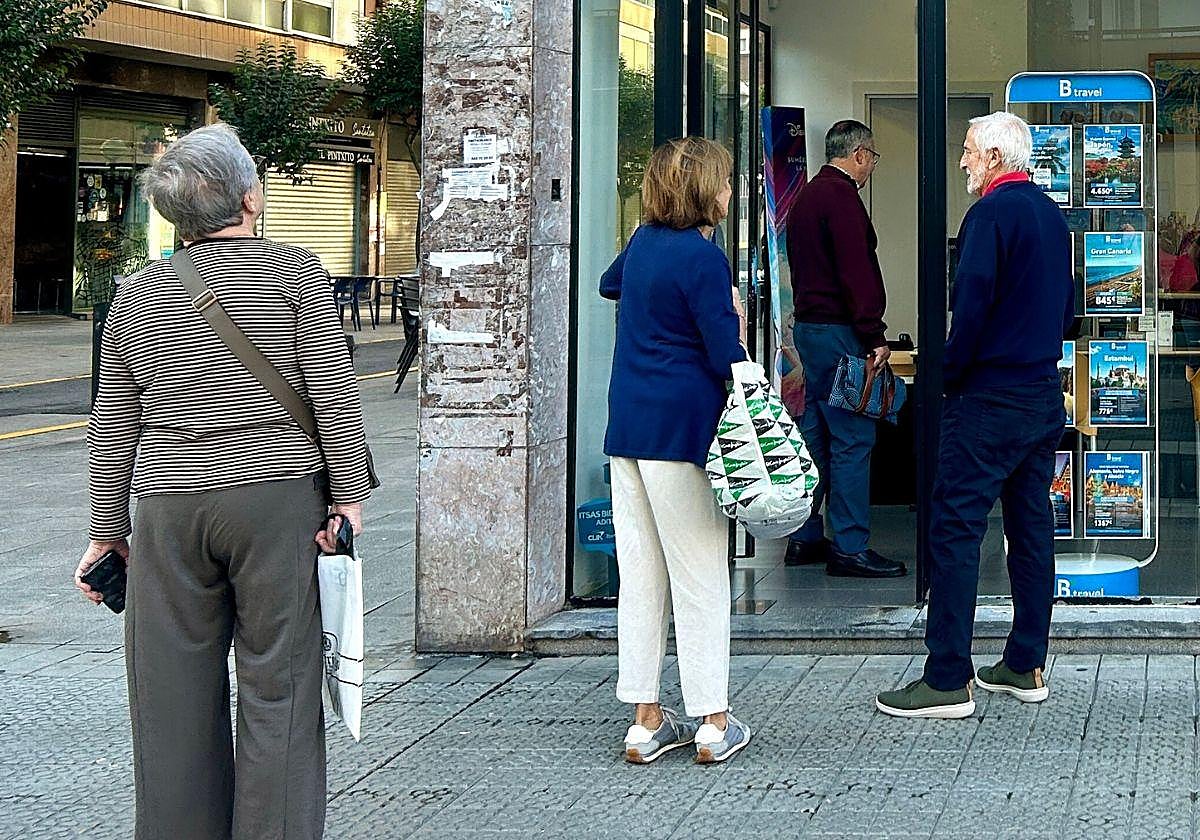 Un grupo de jubilados aguarda en la puerta de una agencia de viajes.