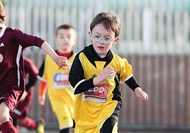 Un niño con gafas juega en un patio de un colegio.