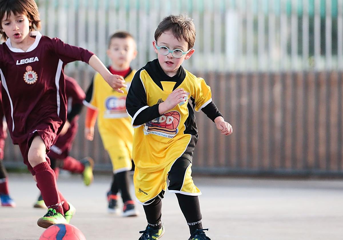 Un niño con gafas juega en un patio de un colegio.