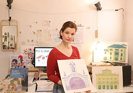 Rodeada de algunas de sus obras y con las acuarelas originales que componene uno de los carteles de Irun.