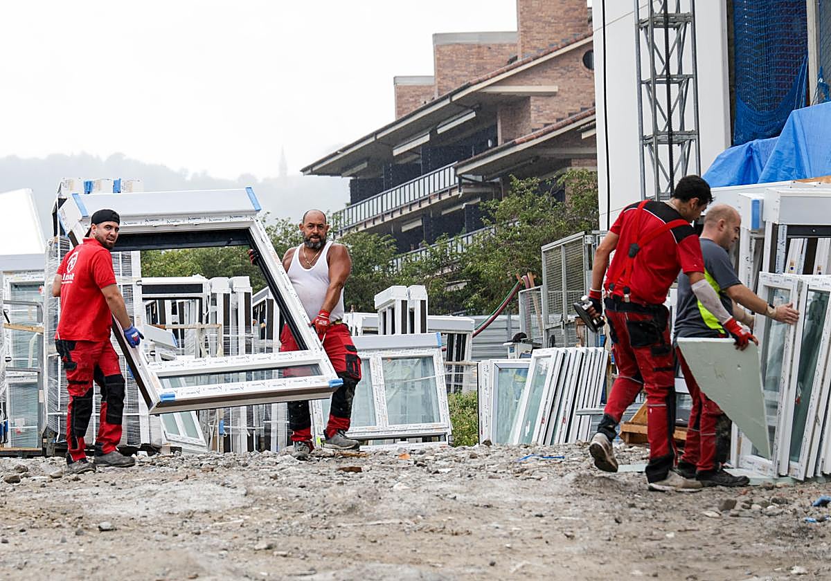 Varios operarios transportan unas ventanas para un edificio de VPO que se construye en Hondarribia.