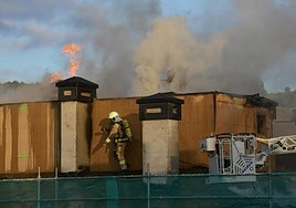 Bomberos trabajando en las labores de extinción en el tejado del edificio