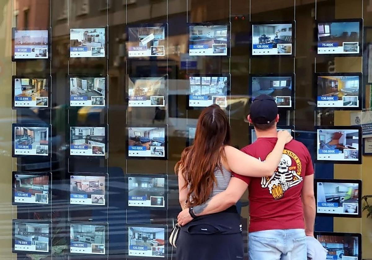 Dos jóvenes observan los anuncios en una inmobiliaria
