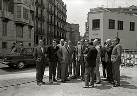 Delante, unas autoridades visitando obras. Detrás, el cine Miramar.