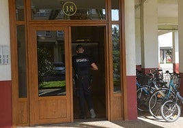 Un ertzaina entrando al edificio donde reside el presunto homicida.