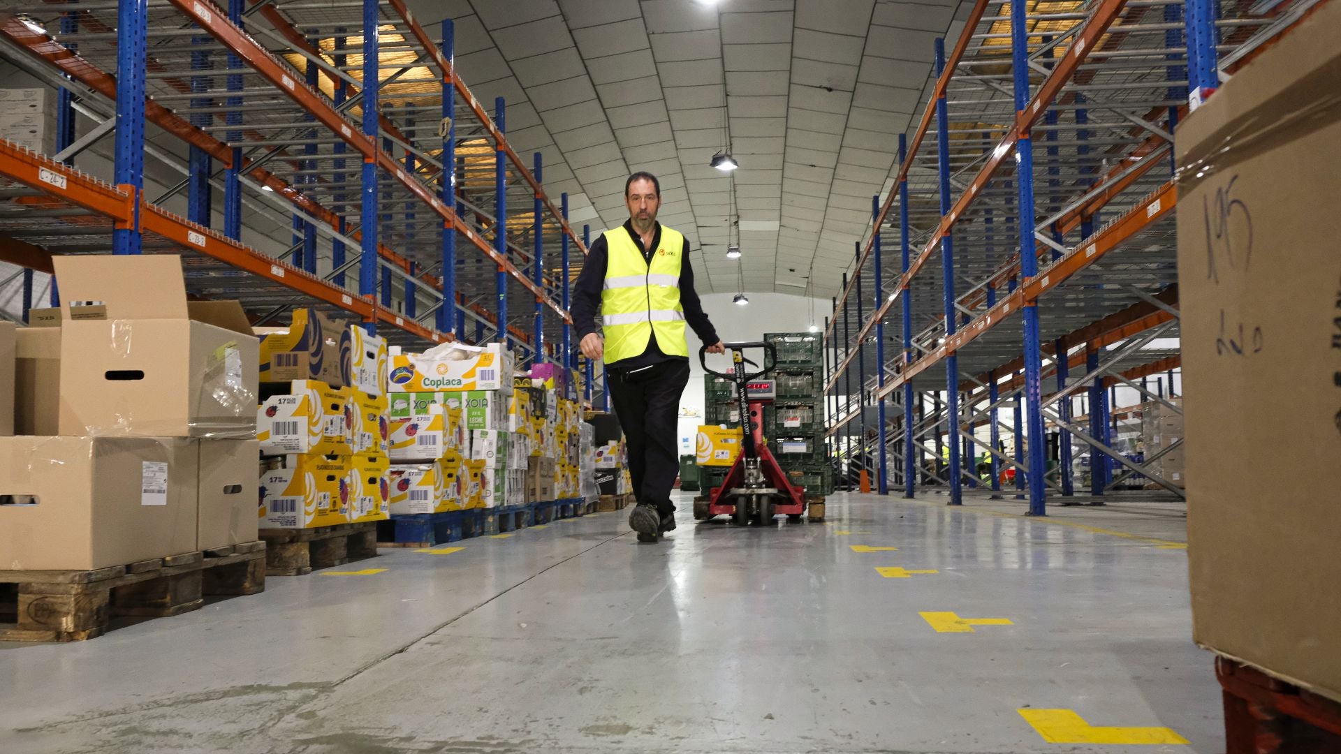 Recogida. Un voluntario transporta un carro, mientras se ven las estanterías vacías de fondo.