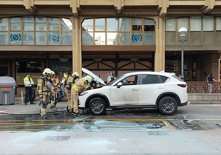 Los bomberos, tras extinguir el fuego en el vehículo incendiado.