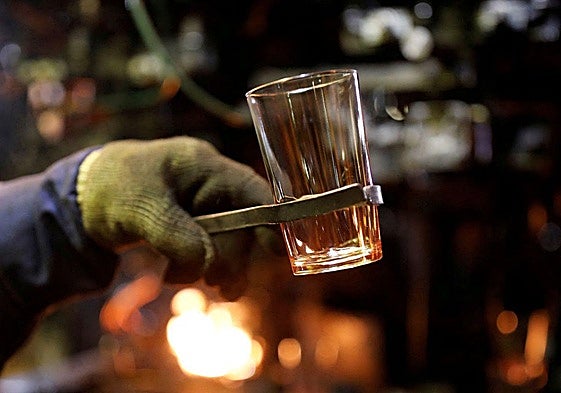 Un trabajador de Duralex sostiene un vaso en uno de los hornos de vidrio de la compañía.