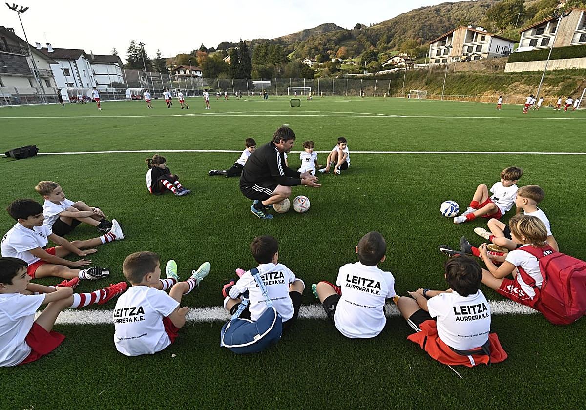 Los niños del Aurrera de Leitza atienden las instrucciones de su entrenador sobre el nuevo césped de Arkixkil.