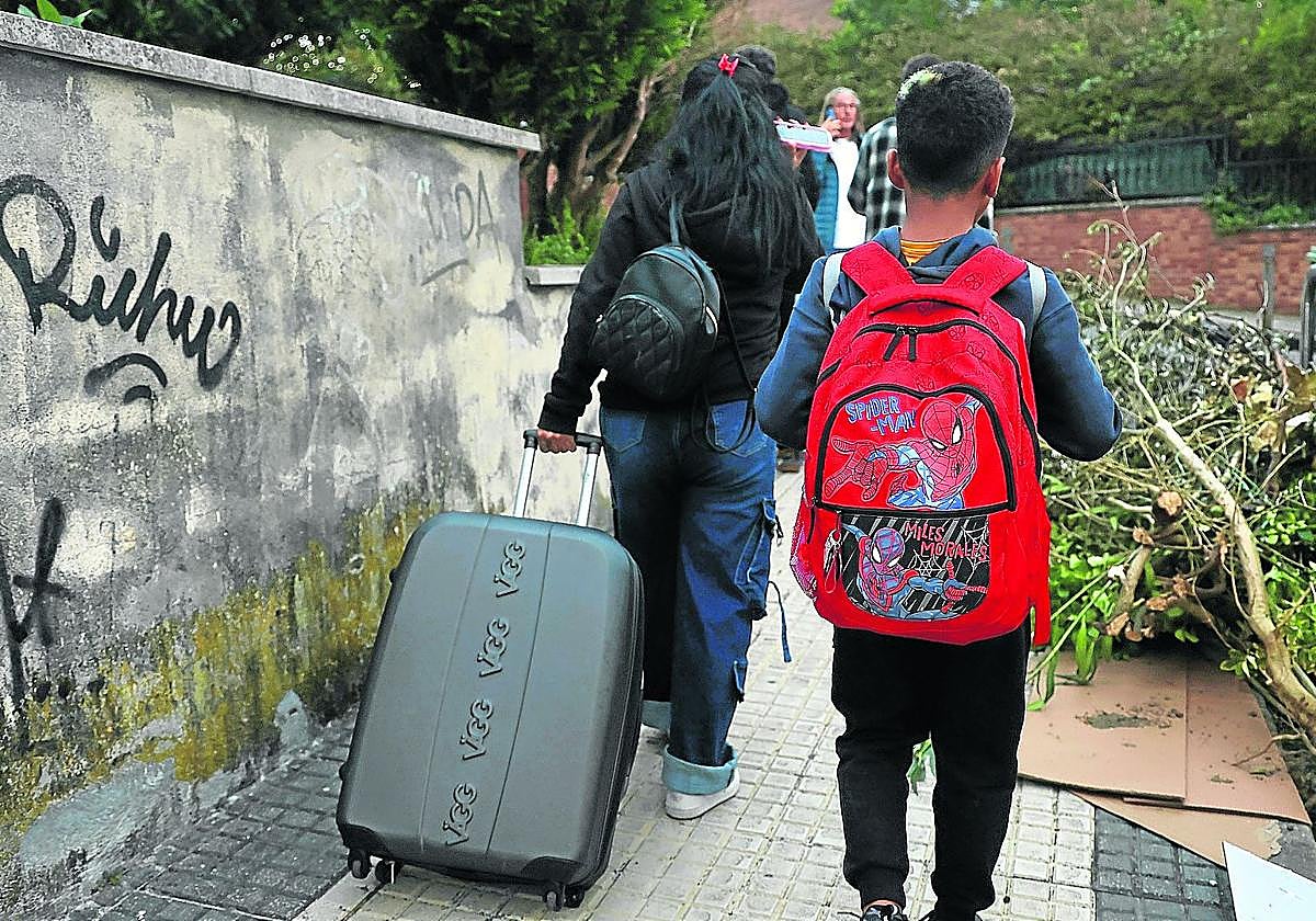 Una de las afectadas transporta junto a su hijo una maleta con los enseres que recogieron de la casa.