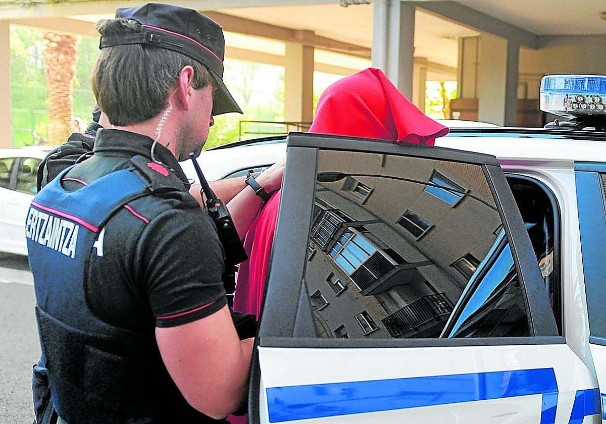 Dos ertzainas introducen en un vehículo al detenido por matar a una mujer en Zarautz.