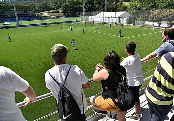 Padres presenciando un partido de fútbol base.