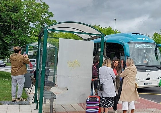 Viajeros esperando al autobús en la marquesina.