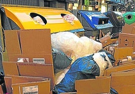 Los contenedores de la calle Fuenterrabía rodeados de cartones de embalaje de los comercios de la zona.