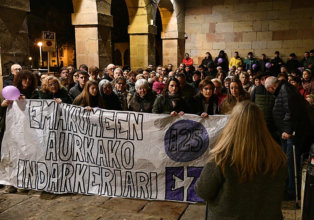 Imagen principal - Olatz se dirige a los vecinos que han acudido a arroparla con globos morados por el 25N y que le entregaron un ramo de flores.