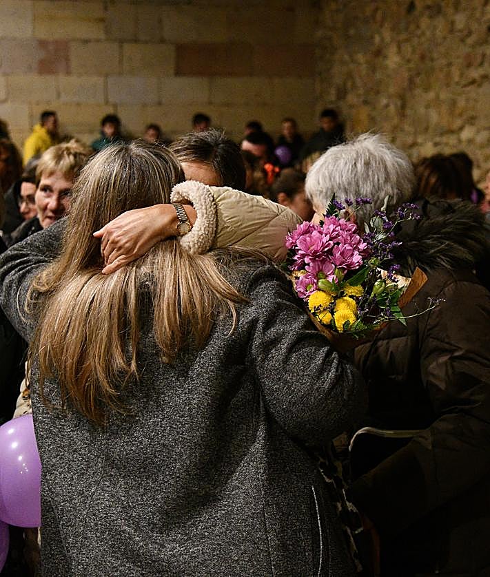 Imagen secundaria 2 - Olatz se dirige a los vecinos que han acudido a arroparla con globos morados por el 25N y que le entregaron un ramo de flores.
