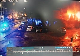 Una cámara de seguridad capta la llegada de la Ertzaintza, a las 4.34 horas, aunque el reloj marca las 5.34. A la derecha de la imagen, el vecino de la caseta de al lado observa la dimensión de las llamas.