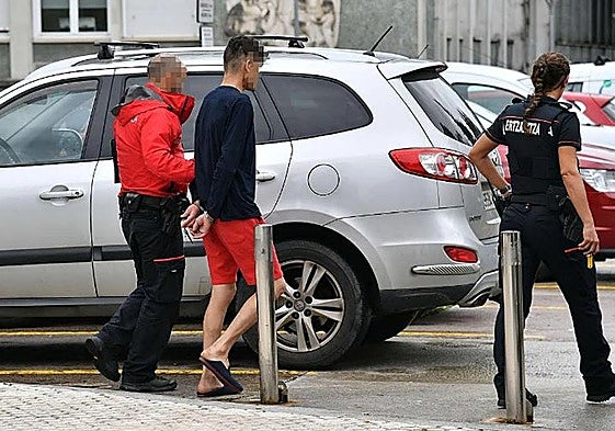 Dos ertzainas trasladan a un detenido en las inmediaciones del Hospital Donostia.