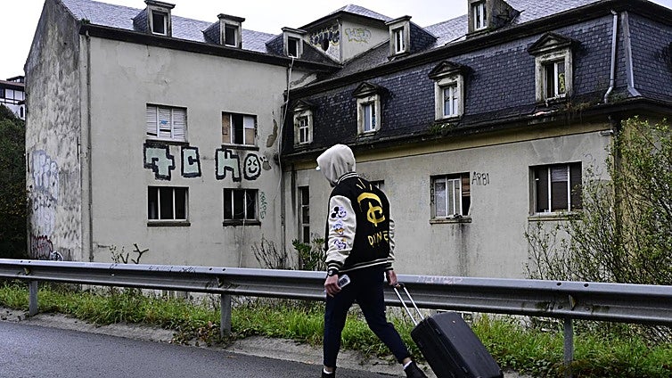 Uno de los jóvenes desalojados ayer por la mañana, con su maleta a cuestas, frente al instituto de Martutene donde residía hasta ahora.