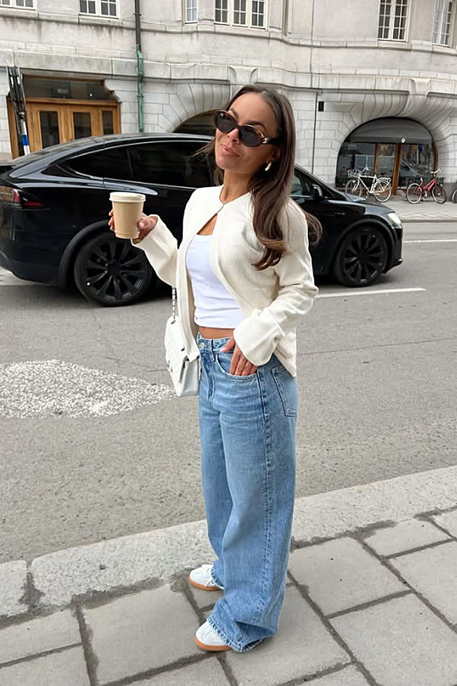Jersey blanco roto abierto, 'top' básico blanco y jeans 'wide-leg' con zapatillas.