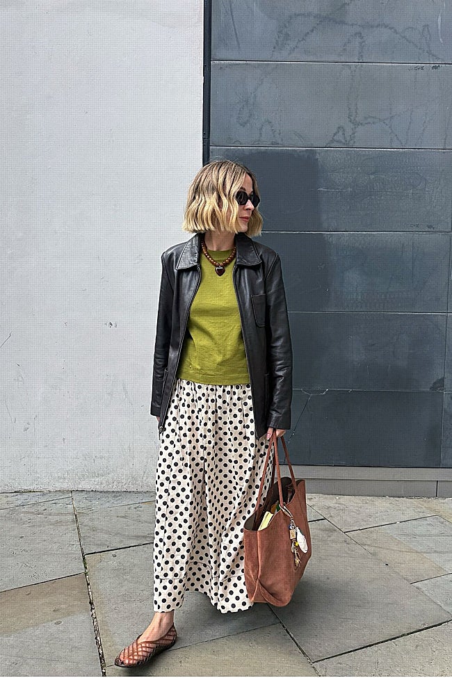Look compuesto por chaqueta de cuero negra, jersey verde lima y falda larga de lunares.