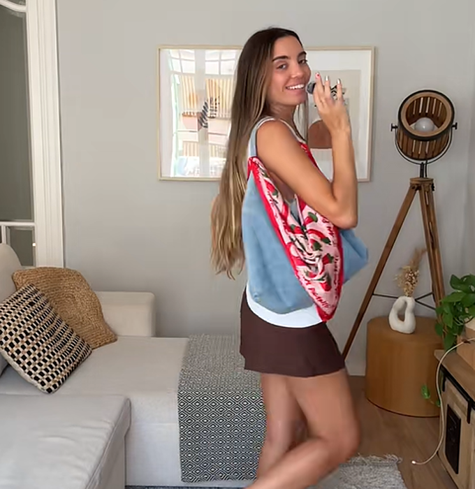 Una mujer mostrando su bolso con un pañuelo atado de las esquinas de las asas.