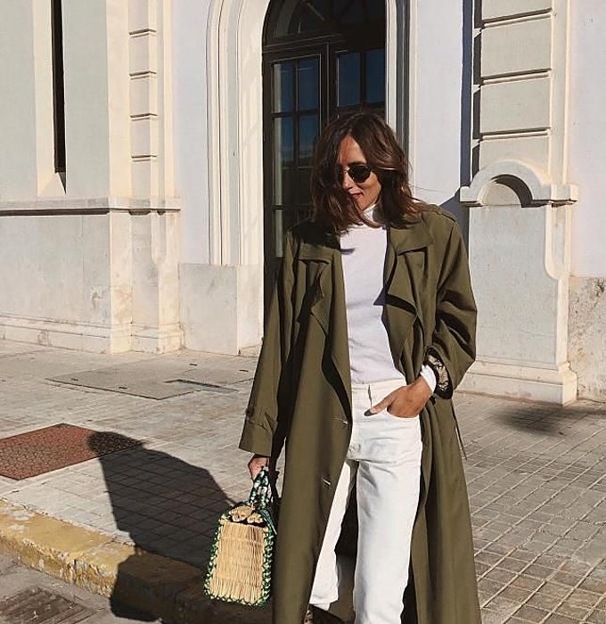 Camiseta blanca con pantalones blancos y gabardina verde.