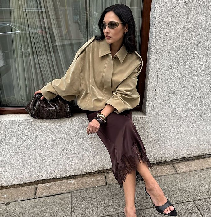 Falda satinada en chocolate con puntilla y chaqueta 'cropped'.
